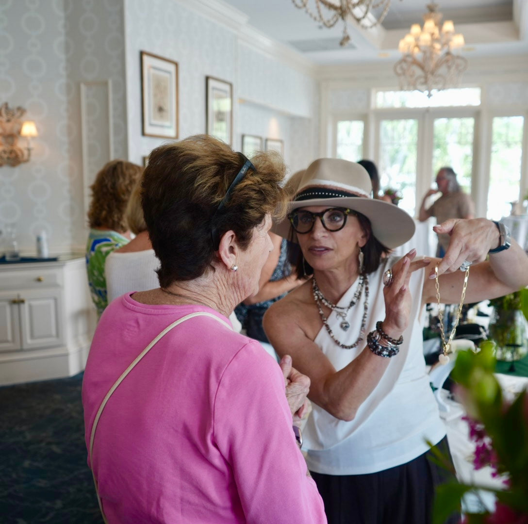 Trunk show table display of MariaRyan Jewelry with Mary Ryan guiding a woman on how to choose her perfect necklace