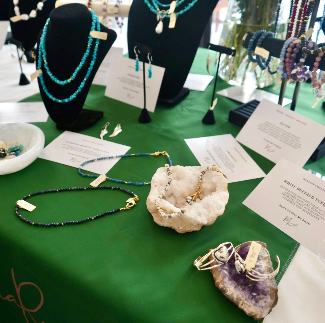 Trunk show display of MariaRyan Jewelry pieces next to crystals, amethyst, and cards that explain each piece's significance