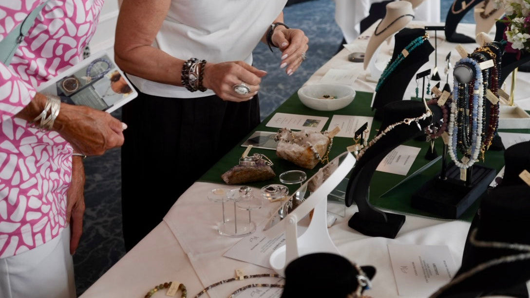 Jewelry display table with various exclusive jewelry pieces at a trunk show event.
