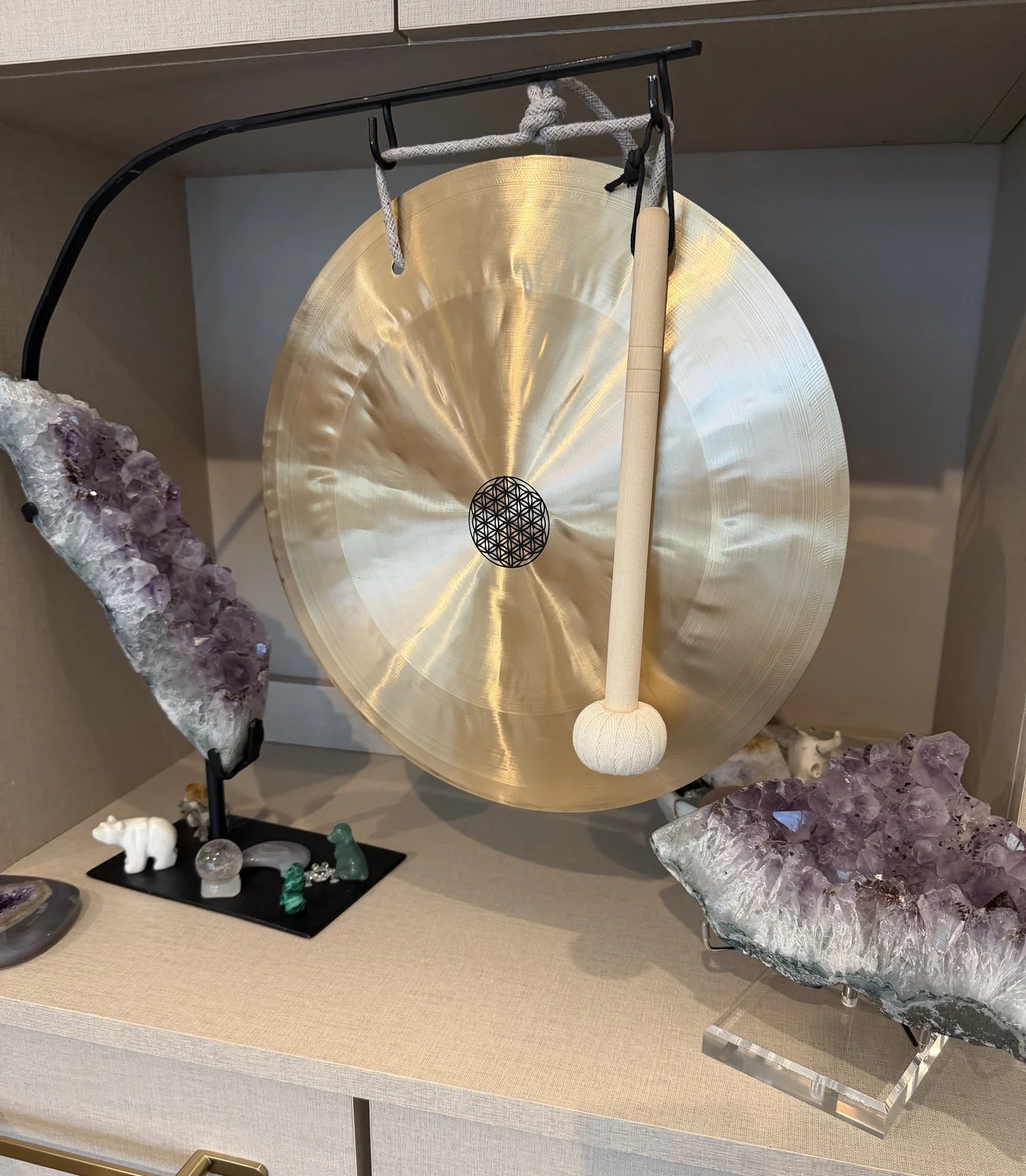Gong on a stand with crystals and amethysts on a shelf