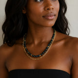 A woman wearing layered necklaces by MariaRyan Jewelry. One has ronud dark teal apitie beads and the other has gold paperclip links.