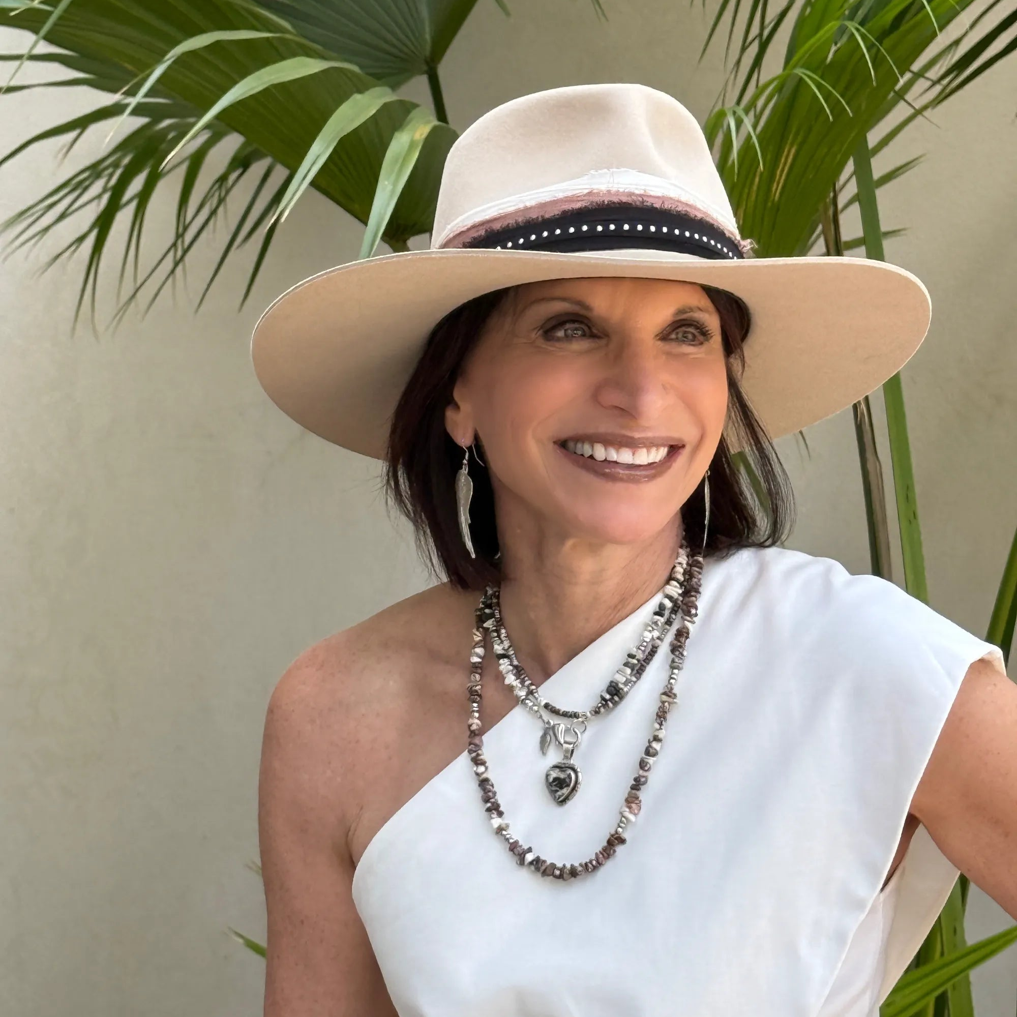 Founder, Mary Ryan, wearing a beige hat and white top with plants in the background